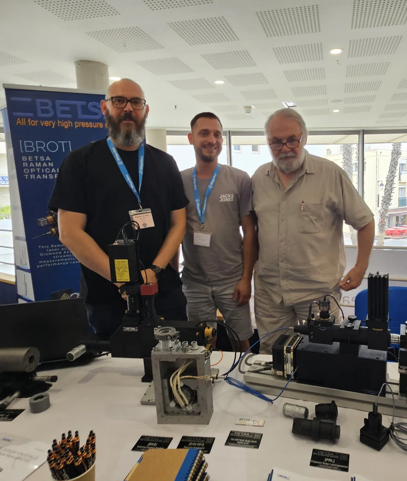 The BETSA&reg; stand at EHPRG 2026 in Palavas-les-Flots: Romain Ciurko with a BROT Raman optical head, a member of the team, and Alain Bourdellot, who ran BETSA&reg; for twenty years